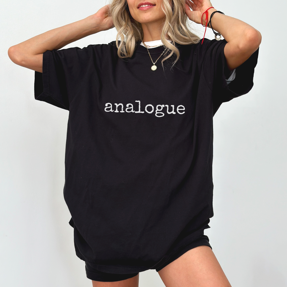 Person wearing a black oversized t-shirt with 'analogue' text on a white background
