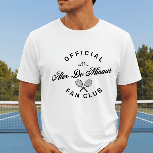 Apparel for Alex De Minaur supporters, showing a white t-shirt with 'Alex De Minaur Fan Club' text, modeled in front of a tennis court.