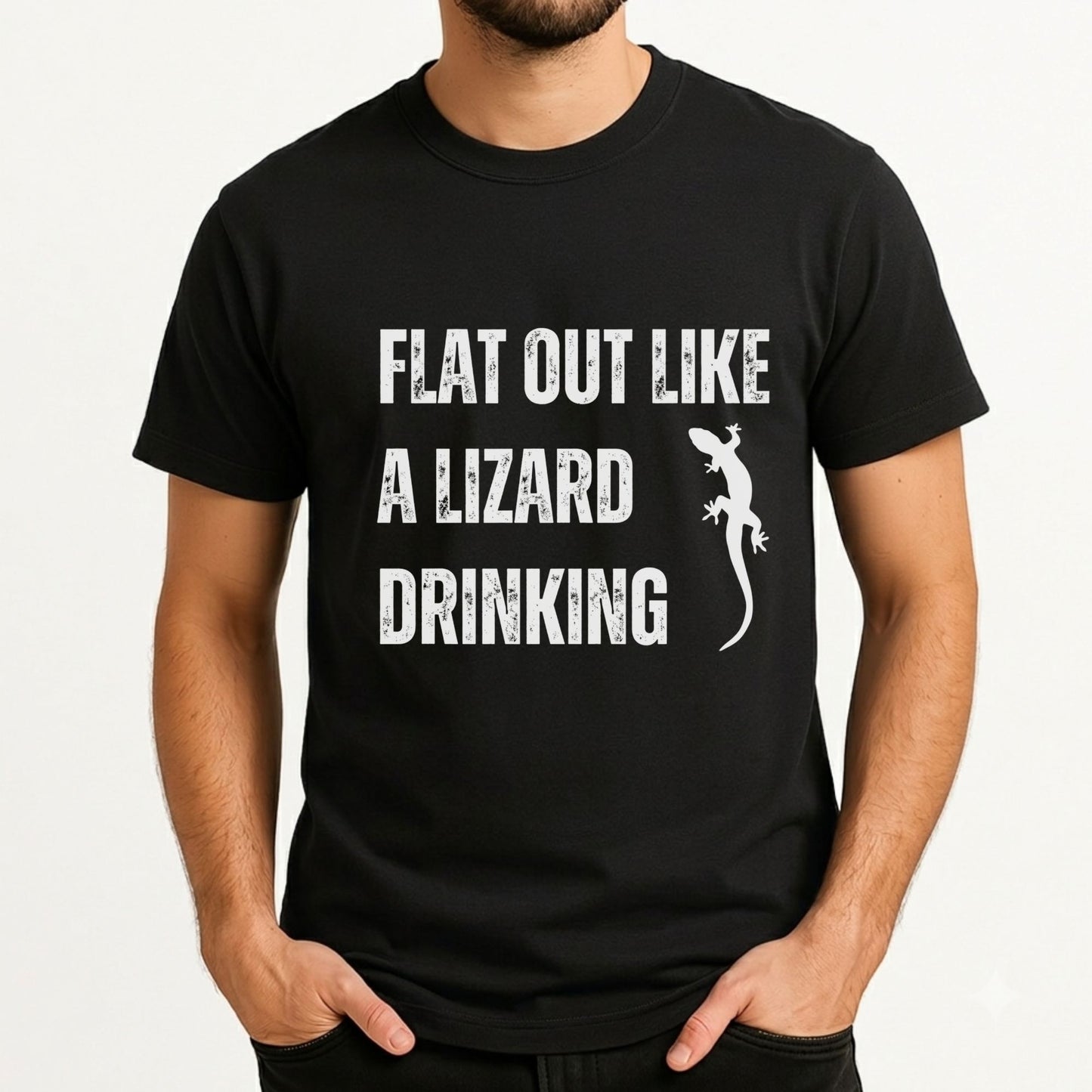 A man wearing a black short-sleeve t-shirt with a distressed white graphic that reads 'FLAT OUT LIKE A LIZARD DRINKING' next to a lizard silhouette.
