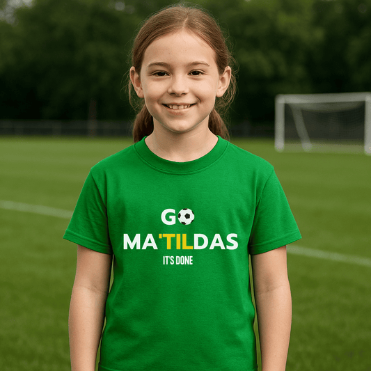 Young girl wearing a green t-shirt with 'GO MATILDAS IT'S DONE' text on a soccer field.
