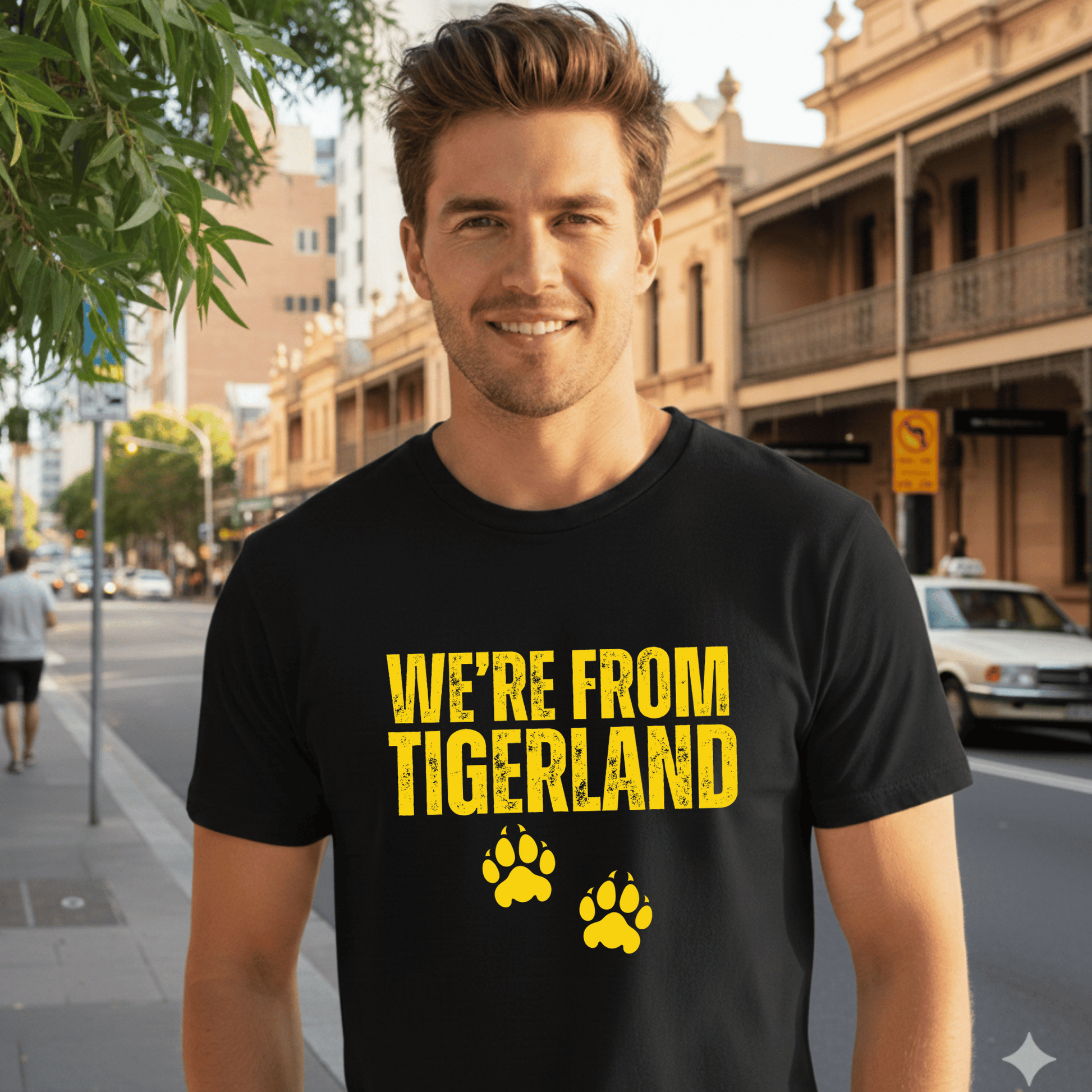 Man wearing a black t-shirt with 'WE'RE FROM TIGERLAND' text and paw prints on a city street.